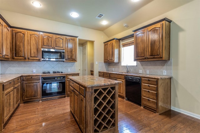 kitchen with sink, dark hardwood / wood-style floors, a center island, black appliances, and light stone countertops