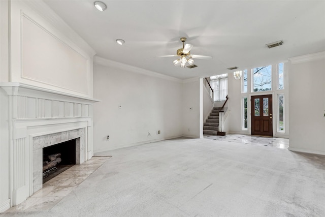 unfurnished living room with light carpet, crown molding, a premium fireplace, and ceiling fan