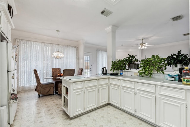 kitchen with decorative light fixtures, kitchen peninsula, white fridge, and white cabinets