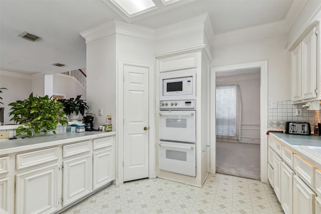 kitchen with white appliances, ornamental molding, decorative backsplash, and white cabinets