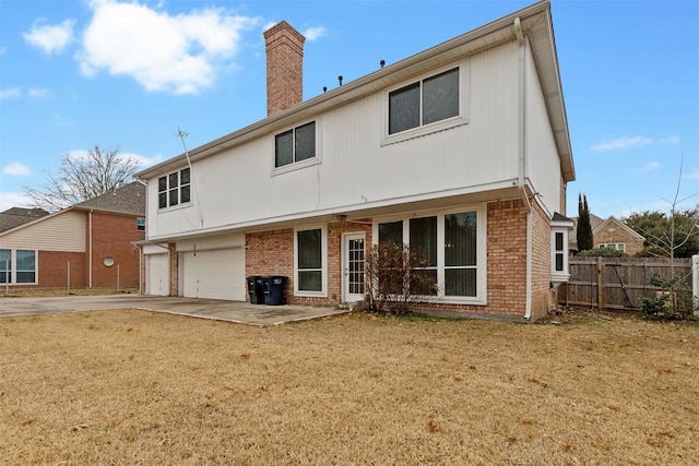 rear view of property with a garage and a lawn