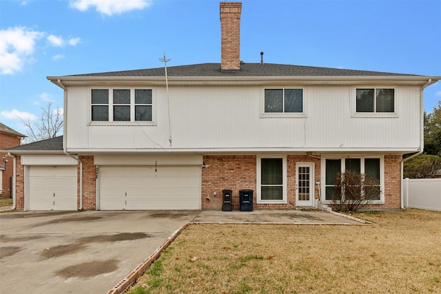 rear view of property featuring a garage and a lawn