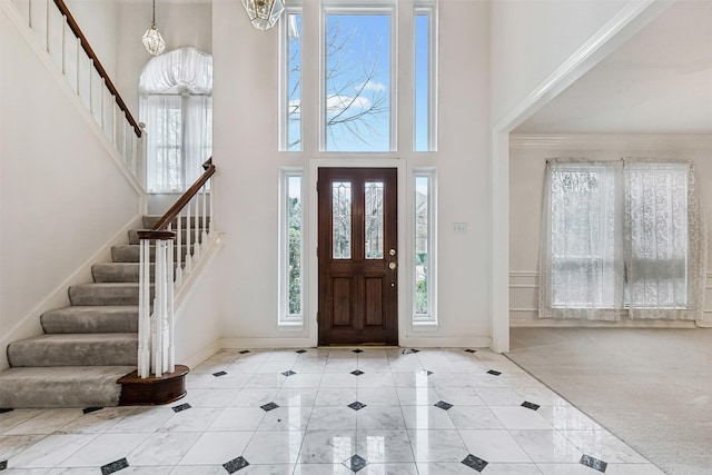 foyer entrance featuring a high ceiling, a wealth of natural light, and light tile patterned floors