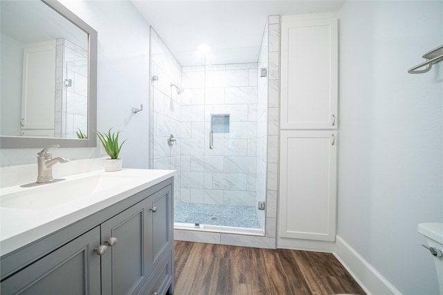 bathroom featuring baseboards, a shower stall, vanity, and wood finished floors