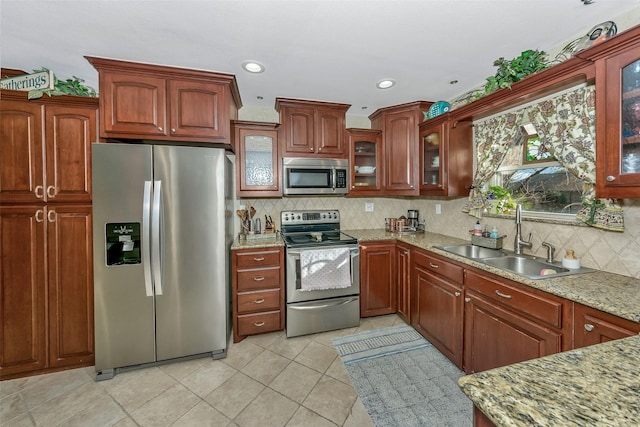 kitchen featuring sink, light stone counters, light tile patterned floors, stainless steel appliances, and decorative backsplash