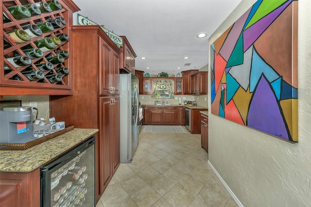 kitchen with light tile patterned flooring, appliances with stainless steel finishes, sink, wine cooler, and light stone countertops