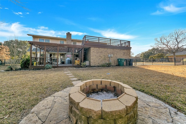 rear view of house featuring a wooden deck, a yard, and a fire pit