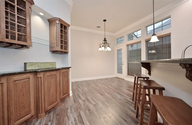 kitchen with an inviting chandelier, hanging light fixtures, crown molding, and hardwood / wood-style floors