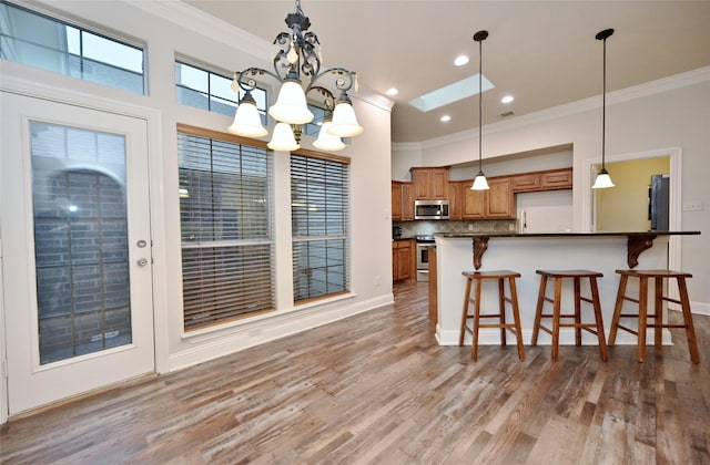 kitchen featuring crown molding, backsplash, stainless steel appliances, a kitchen breakfast bar, and light wood-type flooring