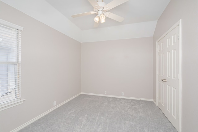 carpeted empty room featuring vaulted ceiling, plenty of natural light, and ceiling fan