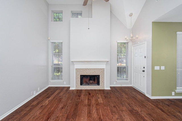 unfurnished living room featuring a tiled fireplace, high vaulted ceiling, dark hardwood / wood-style floors, and ceiling fan