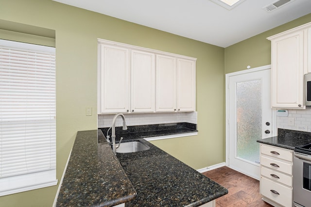 kitchen featuring dark wood-type flooring, sink, white cabinetry, appliances with stainless steel finishes, and dark stone counters