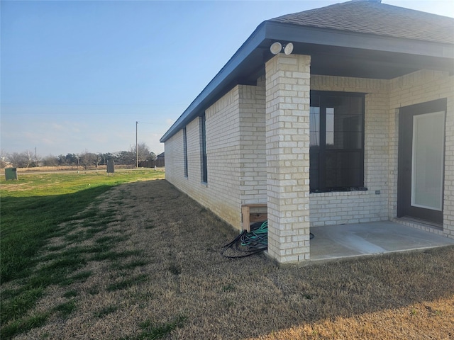 view of side of property with a patio and a lawn