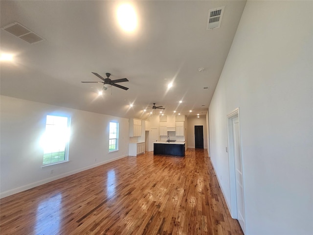 unfurnished living room featuring ceiling fan, wood-type flooring, and sink