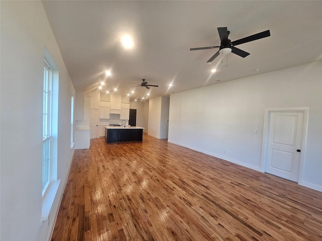 unfurnished living room featuring hardwood / wood-style flooring, ceiling fan, and sink