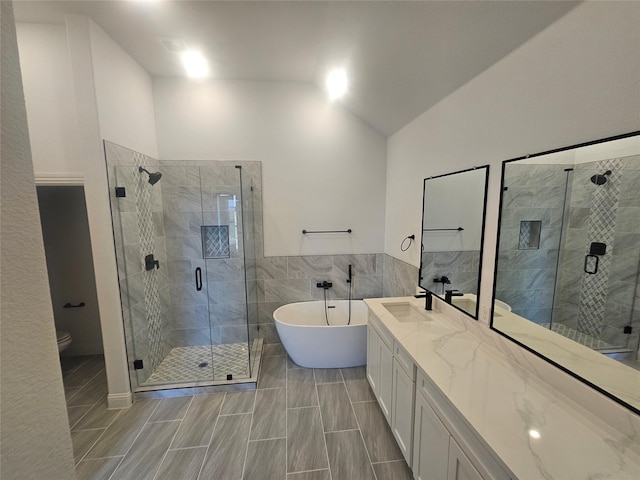 full bathroom with plus walk in shower, vaulted ceiling, tile walls, vanity, and toilet