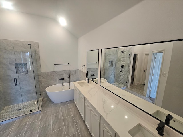 bathroom with independent shower and bath, vaulted ceiling, tile walls, and vanity