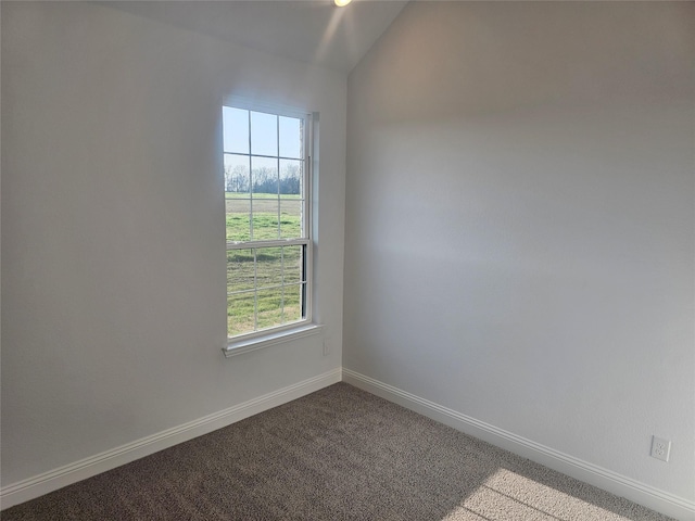 carpeted spare room featuring vaulted ceiling