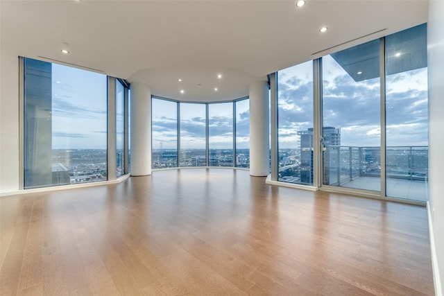 spare room with a city view, floor to ceiling windows, a healthy amount of sunlight, and wood finished floors