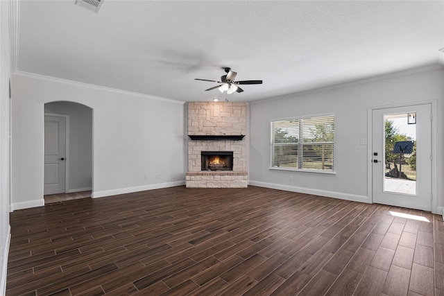 unfurnished living room featuring crown molding, ceiling fan, dark hardwood / wood-style flooring, and a stone fireplace