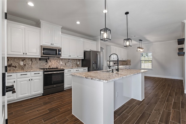 kitchen featuring appliances with stainless steel finishes, light stone counters, white cabinets, a center island with sink, and decorative light fixtures