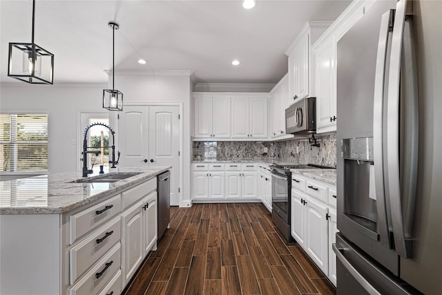 kitchen featuring sink, appliances with stainless steel finishes, hanging light fixtures, an island with sink, and white cabinets