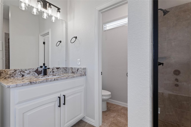 bathroom with tiled shower, vanity, toilet, and tile patterned floors