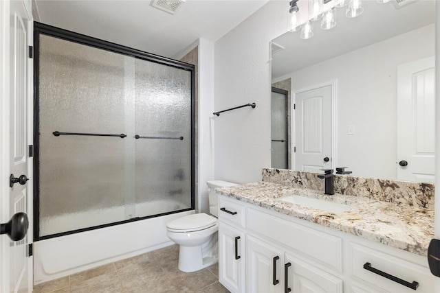 full bathroom featuring vanity, bath / shower combo with glass door, tile patterned floors, and toilet