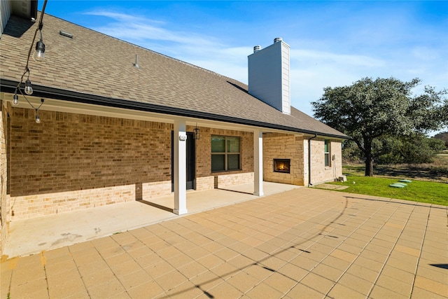 back of house with a patio and an outdoor stone fireplace