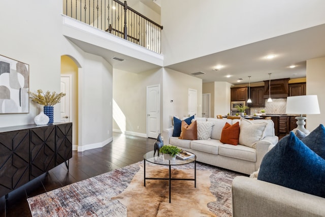 living room featuring a towering ceiling and dark hardwood / wood-style floors