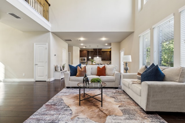 living room with dark hardwood / wood-style flooring and a towering ceiling