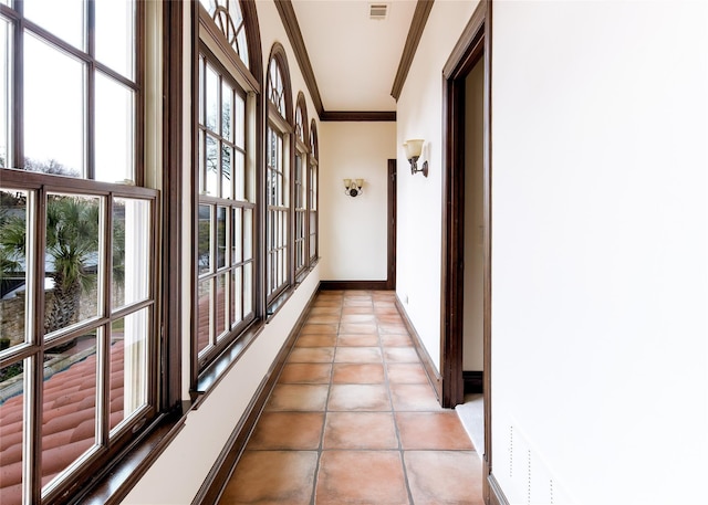 hallway featuring crown molding and light tile patterned floors