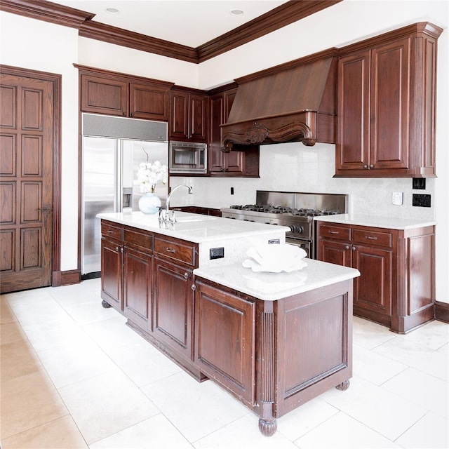 kitchen featuring sink, custom exhaust hood, a kitchen island with sink, built in appliances, and crown molding