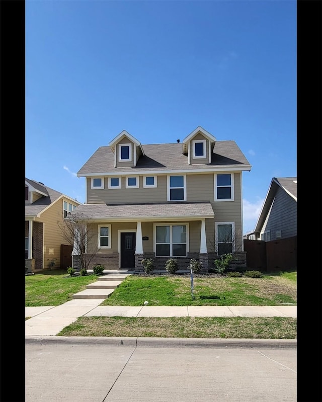 view of front of property featuring a front lawn and roof with shingles