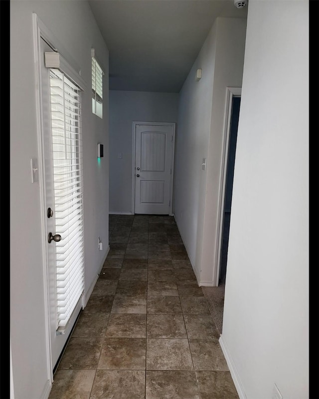 hallway with tile patterned flooring and baseboards