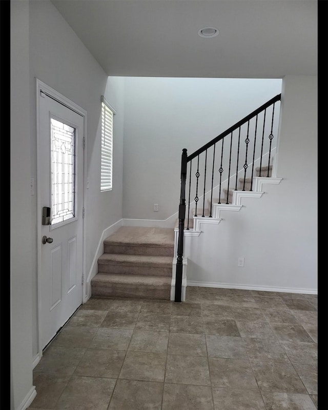 foyer entrance featuring stairs and baseboards