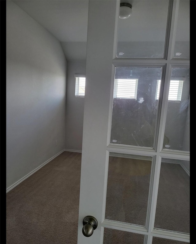 carpeted empty room featuring lofted ceiling and baseboards