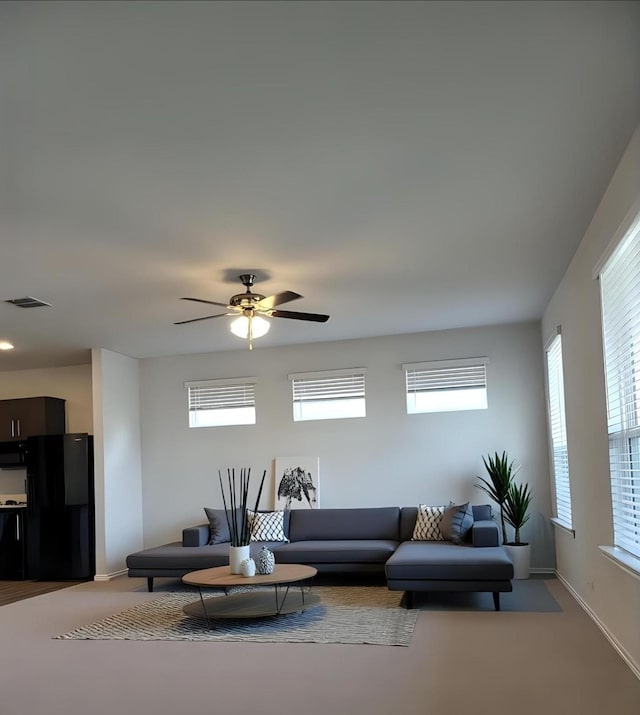 living area with light carpet, plenty of natural light, visible vents, and a ceiling fan