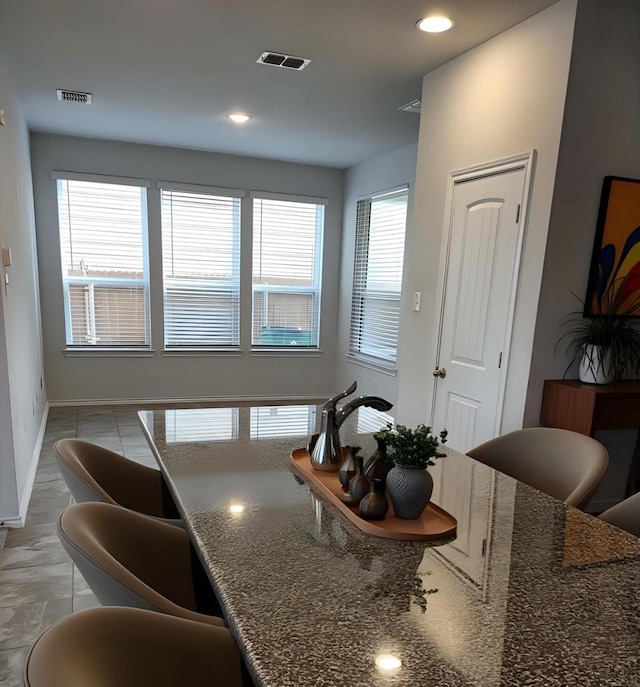 kitchen with baseboards, visible vents, dark stone countertops, and recessed lighting