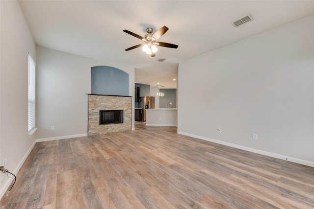 unfurnished living room featuring ceiling fan, a stone fireplace, and light hardwood / wood-style flooring