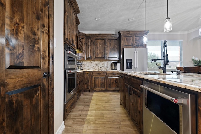 kitchen with light stone counters, crown molding, decorative light fixtures, dark brown cabinets, and stainless steel appliances