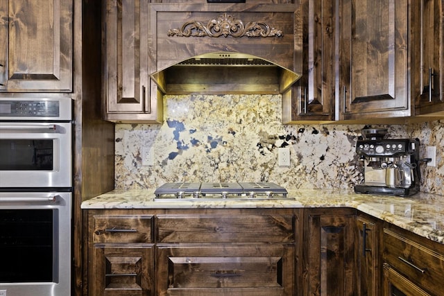 kitchen with tasteful backsplash, premium range hood, appliances with stainless steel finishes, and dark brown cabinetry