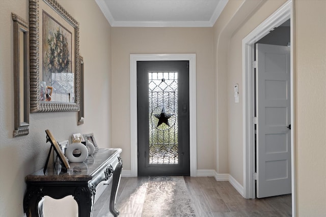 foyer entrance with hardwood / wood-style flooring, ornamental molding, and a healthy amount of sunlight