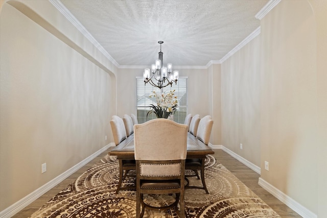 dining area featuring hardwood / wood-style flooring, ornamental molding, a notable chandelier, and a textured ceiling