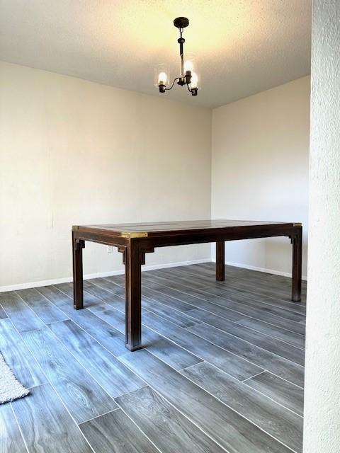 rec room featuring dark wood-type flooring, a textured ceiling, and a chandelier