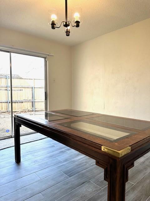 game room with dark hardwood / wood-style flooring, a notable chandelier, and a textured ceiling