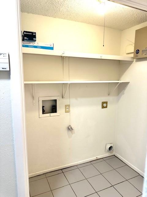 clothes washing area featuring tile patterned flooring, hookup for an electric dryer, washer hookup, and a textured ceiling