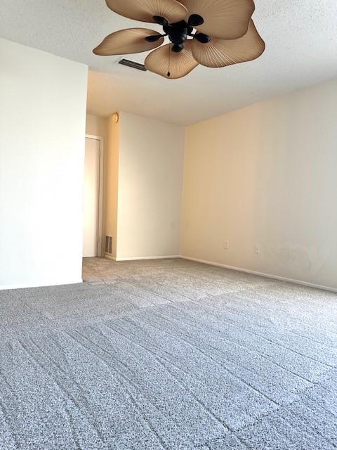 empty room featuring ceiling fan, carpet flooring, and a textured ceiling