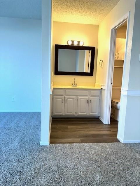 bathroom with vanity, toilet, and a textured ceiling