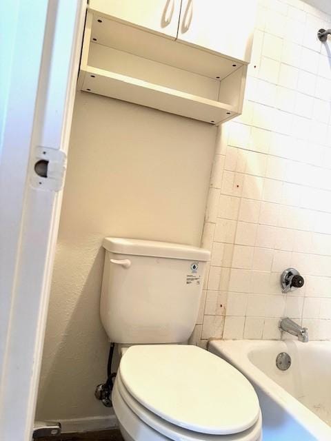 bathroom featuring tiled shower / bath and toilet